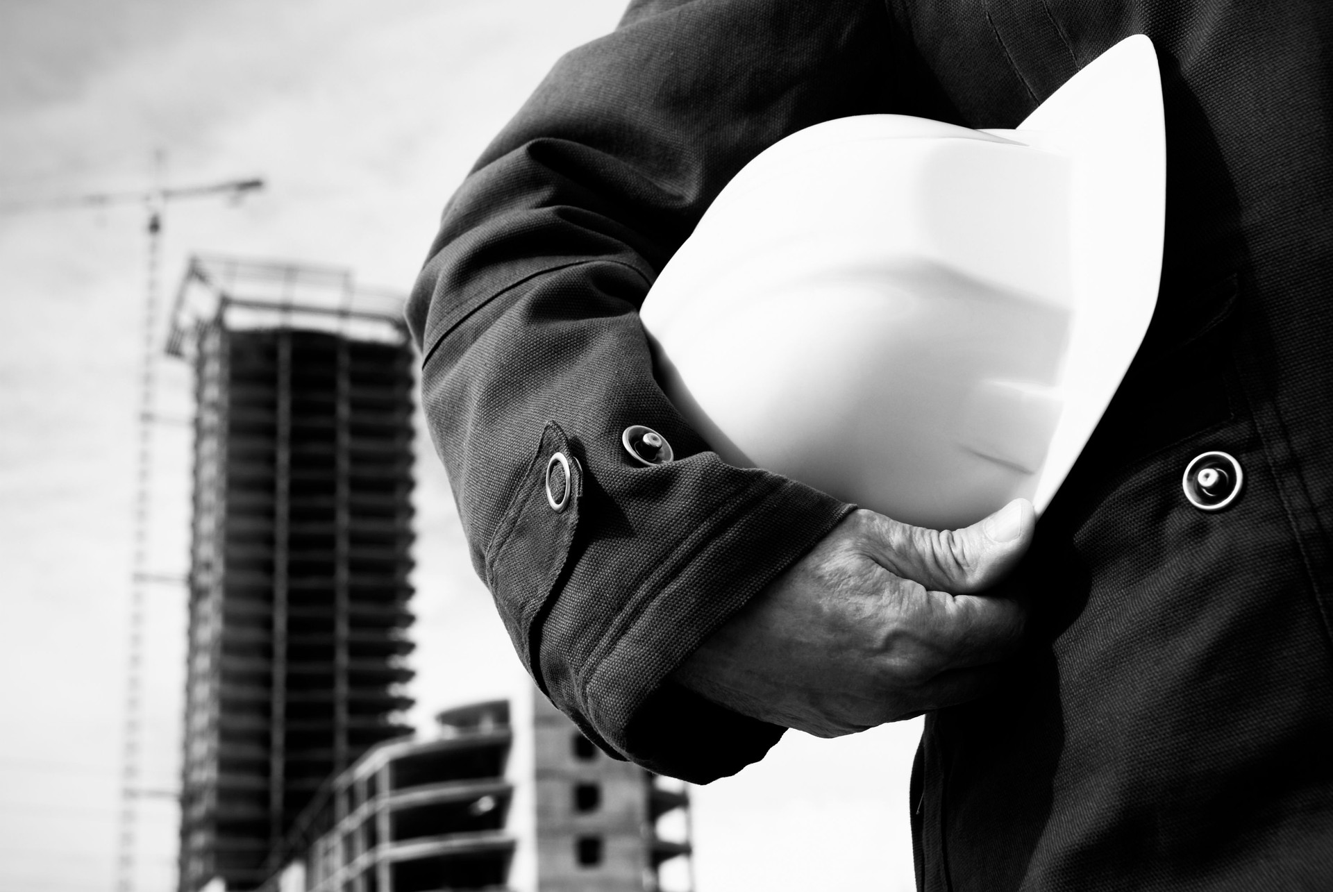 Black and gray image of a hard hat under a man's arm